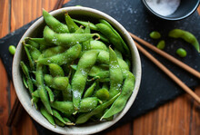 Steamed Edamame Sprinkled With Sea Salt On A Dark Stone Board, Top View