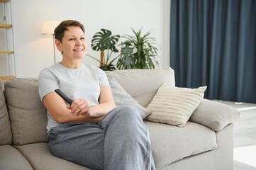 Sticker - Portrait of happy older woman changing channel on television.