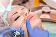© Vera - Lip augmentation. Beautician injects hyaluronic acid into the lips of a girl with a syringe. The cosmetologist doctor performs the procedure in the cosmetology office. Plastic surgery.