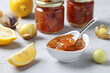 Homemade transparent physalis jam with lemon in bowl and glass jars on gray background