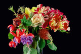 Fototapeta Kwiaty - A bouquet of different colored flowers inside a glass vase isolated on black