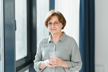 Sticker - age, health care and people concept - happy senior woman with glass of water at home