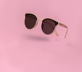 Wall Mural - Soaring trendy sunglasses on pink background with shadow