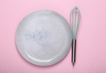 Empty Ceramic Plate With Whisk On Pink Background. Top View