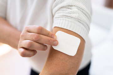 woman applying patch on her arm