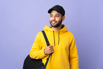 Young sport Moroccan man with sport bag isolated on purple background thinking an idea while looking up