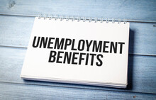 Unemployment Benefits Words On The Notepad And Wooden Background