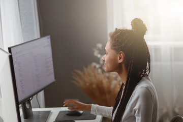 Wall Mural - beautiful mixed-race female coder working on new project texting on computer in apartment