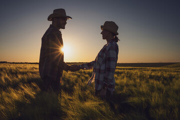 Man and woman are working together in partnership. They are cultivating barley.