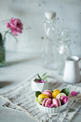 Wall Mural - Good morning. Delicious macarons desserts are served on the table in the morning for breakfast. Beautiful light still life with a rose highlight. Baking for breakfast on a light table with copy space