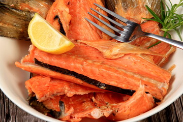 Wall Mural - Hot smoked salmon, trout bones, fork on white plate. Dark wooden board background.