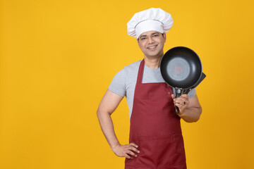 Chef cook man. Cook with frying pan in hand. Chef guy on yellow background. Young man works as chef in restaurant. Cook student is engaged in cooking. Career in field of HoReCa. Cafe employee portrait