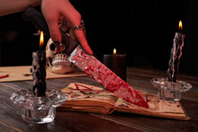 Antichrist Satanic Wiccy Blood Sacrifice Ritual Concept. Female Hand Holds Bloody Knife Close-up.