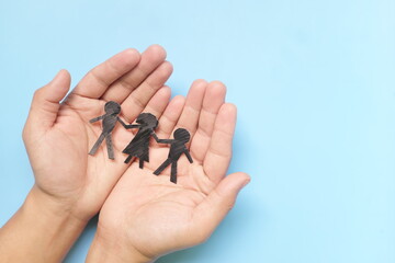 Hand holding children paper cutout. Child abuse rehabilitation, custody, human rights and refugee care and protection concept.