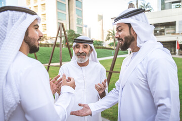 Wall Mural - Three business men walking in Dubai wearing traditional emirati clothes