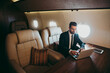 © oneinchpunch - Businessman flying on his private jet. Business man flying on the private airplane. Working during the flight to his meeting. Concept about transportations and salespeople