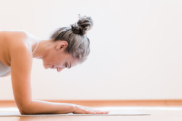 Side view of the senior healthy woman workout at home, making exercise, doing yoga, standing at the plank. Home fitness concept