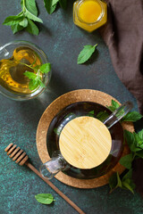 Wall Mural - Therapeutic herbal green tea. Hot tea with honey mints in a glass teapot on a stone table. Top view flat lay.