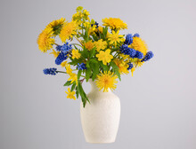 Bouquet Of Various Wildflowers In A Ceramic Vase With A Handle On A Gray Background