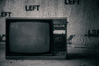 Old broken TV in an abandoned building. Terrible atmosphere. Monochrome photo. Broken item. Concrete wall.