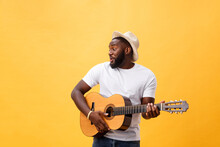 Muscular Black Man Playing Guitar, Wearing Jeans And White Tank-top. Isolate Over Yellow Background.