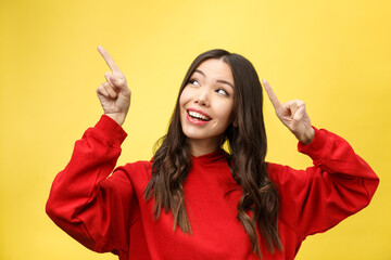 Wall Mural - Young beautiful asian woman pointing to copyspace, isolated on yellow background