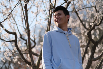 Wall Mural - happy smiling Asian young under white sakura blossom tree