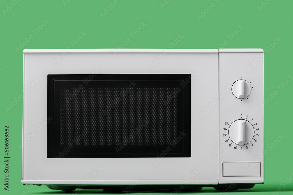 White microwave oven on green background