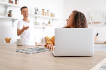  Young couple with laptop talking in kitchen