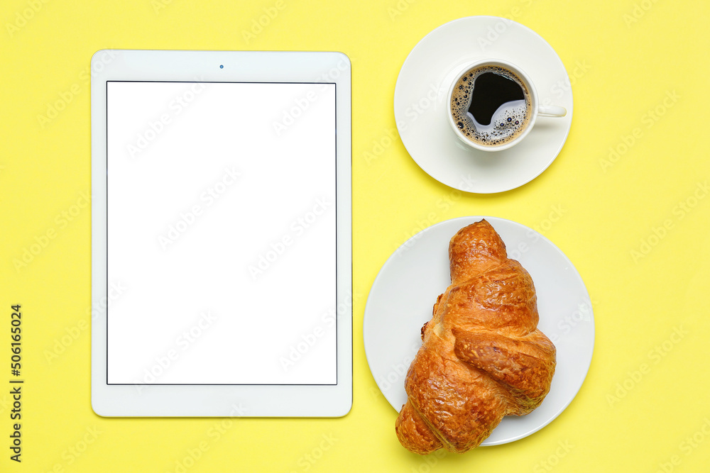 Composition with cup of coffee, tasty croissant and tablet computer on yellow background