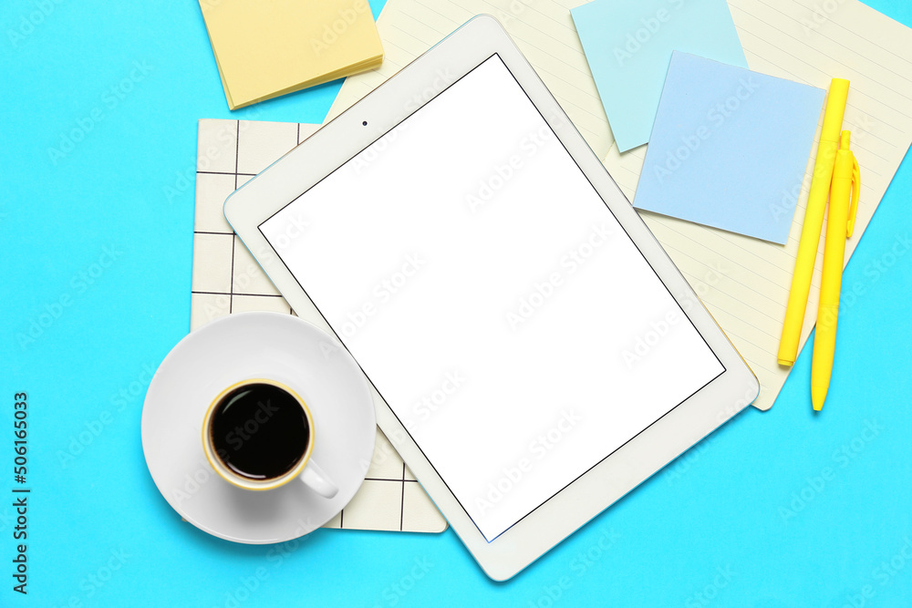 Composition with tablet computer, cup of coffee and stationery supplies on blue background