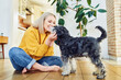© baranq - Smiling woman playing with her dog indoors
