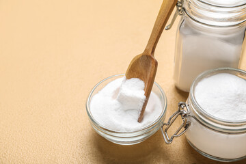 Jars and bowl with baking soda on beige background