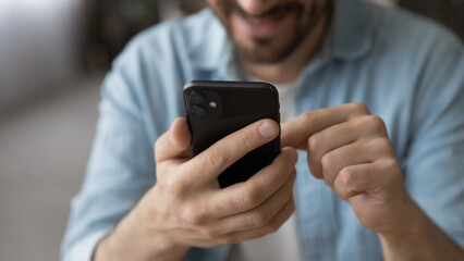 Wall Mural - modern tech. close up cropped view of young guy user holding smartphone gadget using social media ap