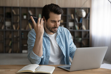 Wall Mural - learning process. millennial man student prepare for exam at home listen to audio information using 