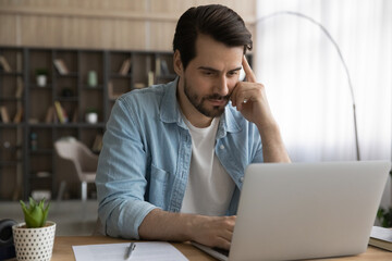 Wall Mural - engaged in work. thoughtful young man freelancer concentrate on solving business problem using lapto