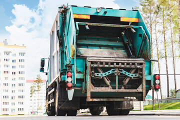 Fototapete - A garbage truck picks up garbage in a residential area. Loading mussar in containers into the car. Separate collection and disposal of garbage. Garbage collection vehicle.