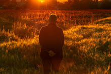 Silhouette Of A Man Isolated On A Background With Field Of Poppies At Sunset

