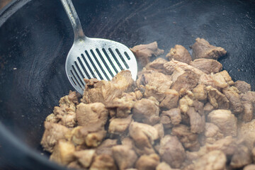 street lighting. fire. a cooking pot. meat is fried. close-up