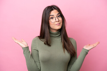 Wall Mural - Young Brazilian woman isolated on pink background With glasses and having doubts