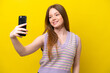 © luismolinero - Young caucasian woman isolated on yellow background making a selfie