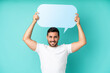 © luismolinero - Young handsome caucasian man isolated on blue background holding an empty speech bubble