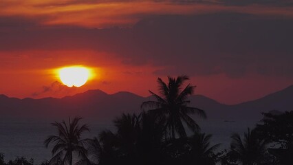 Wall Mural - Tropical Sunset time lapse in Ao Nang, Thailand view over city, sea, jungle and mountains, 4K. Large Sun hides behind the horizon line