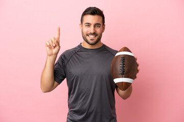 Wall Mural - Young caucasian man playing rugby isolated on pink background pointing up a great idea