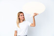 © luismolinero - Blonde Uruguayan girl isolated on white background holding an empty speech bubble