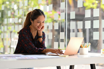 Asian female software designer works on a Ux and Ui Mobile App Template, Freelance programmer working with laptop.