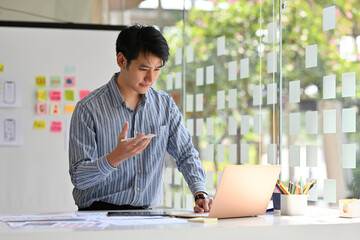 Young Asian man UX designer working with laptop at office, Website designer, Creative planning phone app development template layout framework, User experience concept.