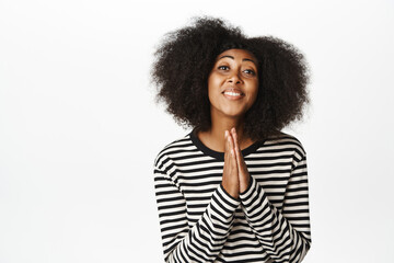 Wall Mural - Portrait of Black girl asking for help, say please, begging, yearning to achieve smth, holding hands in pleading gesture, standing over white background