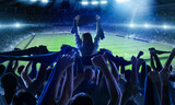 Fototapeta  - Back view of football, soccer fans cheering their team with scarfs at crowded stadium at evening time. Concept of sport, support, competition. Out of focus effect