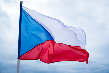 Czech flag waving in wind. Flag of Czech Republic on white cloudy sky background.